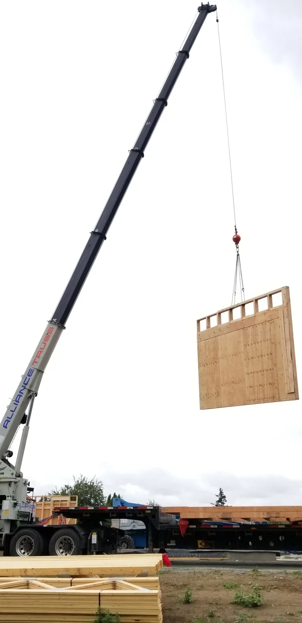 Large industrial crane lifting a wooden crate onto a flatbed truck at a loading facility.