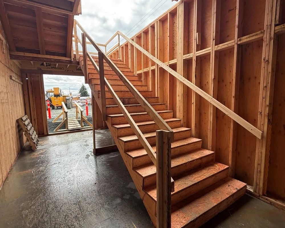 Wooden staircase with metal railings inside a residential construction frame.