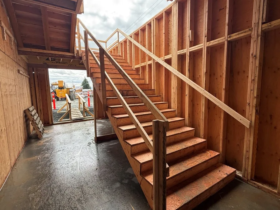 Wooden staircase with metal railings inside a residential construction frame.