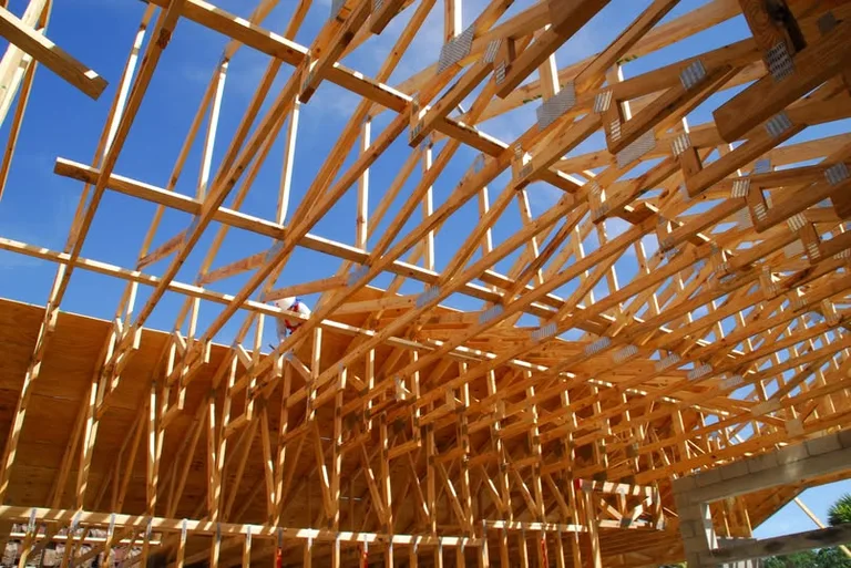 Wooden roof framing structure under construction against clear blue sky